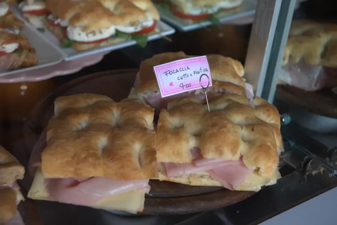 close up of a sandwich made with focaccia salami and fontina cheese in a delicatessen window in Italy.