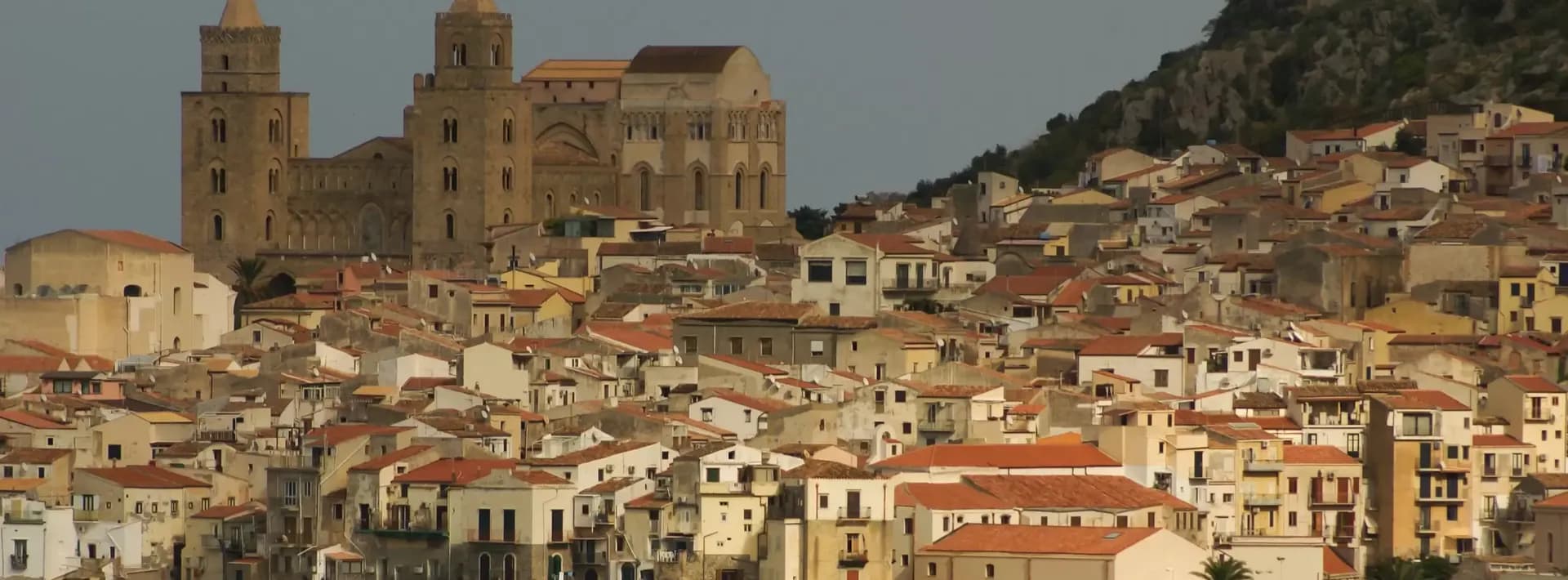 houses along the shoreline and cathedral in background cefalu