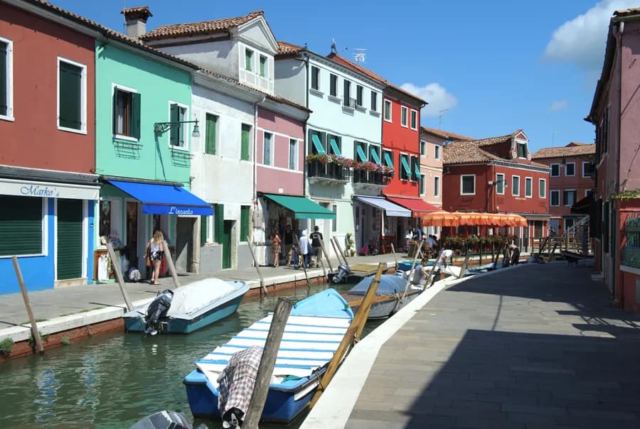 View looking up a canal with anchored boats and colorful buildings in Burano, Italy