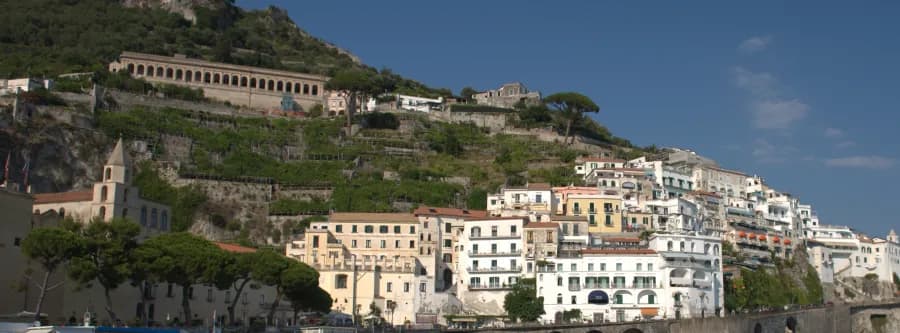 people swimming along the shoreline with a city in the background on the Amalfi Coast