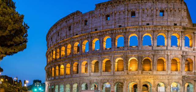 Partial view of arched facade of Colosseum at dusk