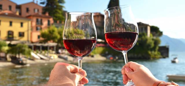 Two glass of red wine toasting with Lake Como in the background