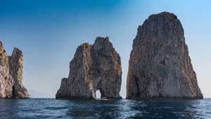 View of Faraglioni cliffs jutting out of the sea at Capri Island in Italy